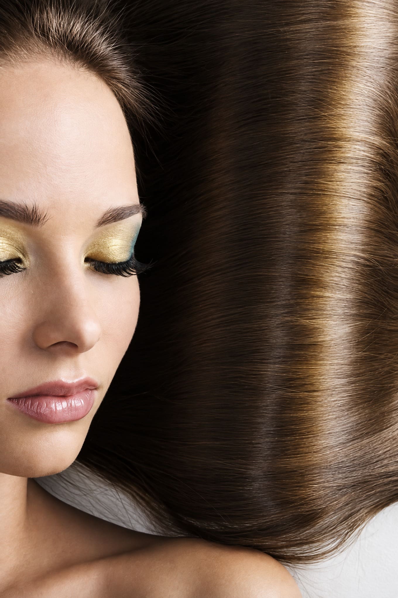Close-up van glanzend lang bruin haar met gouden oogmake-up